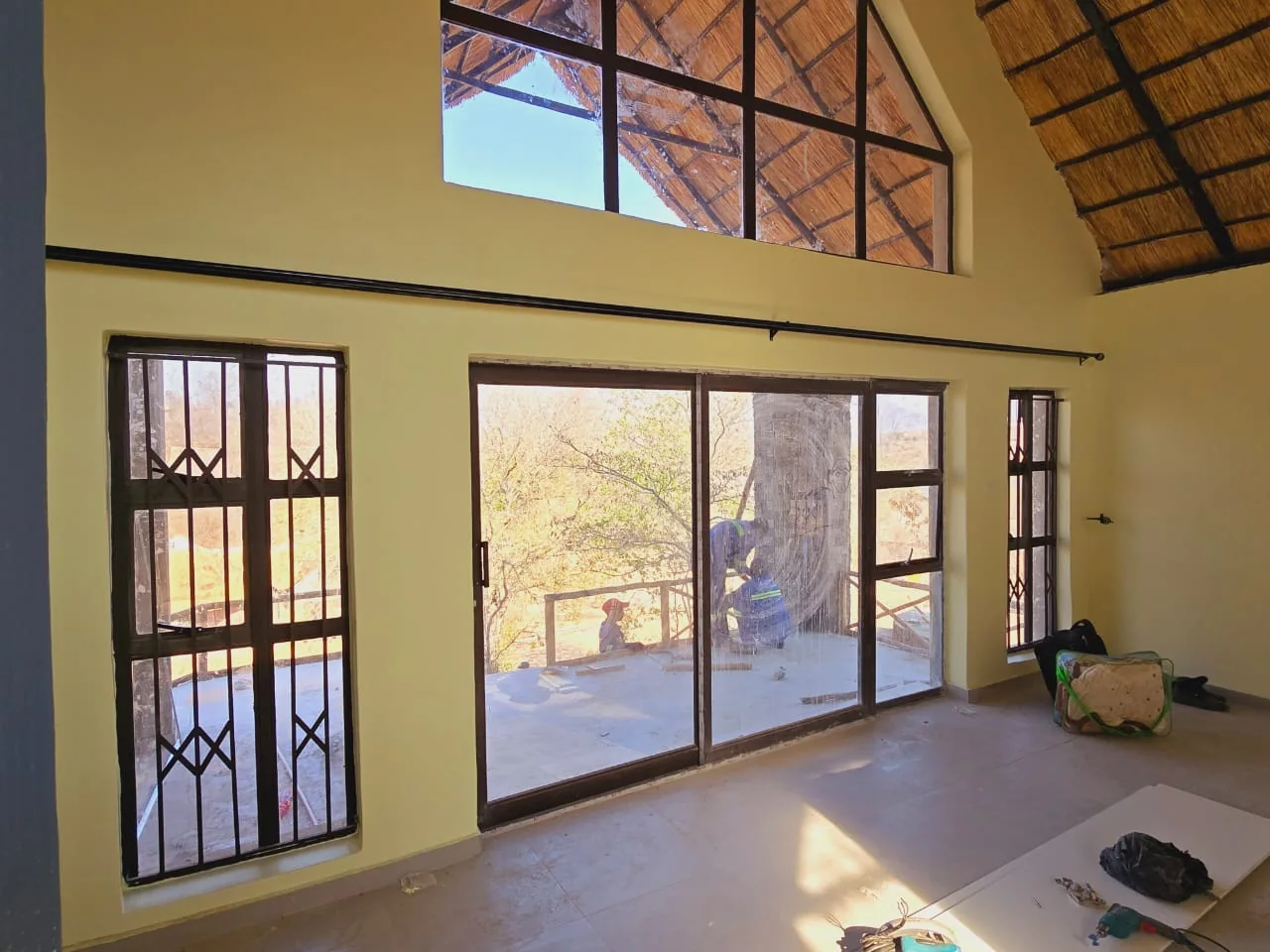 A finished lodge room with tiled floor and full-height glazing under the thatch